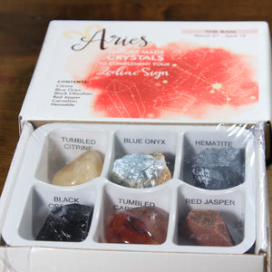 Aries Horoscope Crystals from Rock Paradise. Photo shows a white box that has a pink colored ink blot with the Aries constellation and illustrations of gemstones. The box reads "Aries nature made crystals to complement your zodiac sign. The Ram. March 21-April 19. Contents: Citrine, Blue Onyx, Black Obsidian, Red Jasper, Carnelian, Hematite."