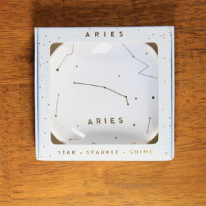 Aries Zodiac Ring Dish from Lucky Feather. Light blue colored ring dish with gold print. Ring dish says Aries and has an illustration of the Aries constellation.