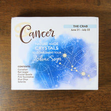 Load image into Gallery viewer, ancer Horoscope Crystals from Rock Paradise. Photo shows a white box that has a blue colored ink blot with the Cancer constellation and illustrations of gemstones. The box reads "Cancer nature made crystals to complement your zodiac sign. The Crab. June 21-July 22. Contents: Carnelian, Red Jasper, Crystal Quartz, Pink Tourmaline, Blue Onyx, Selenite."