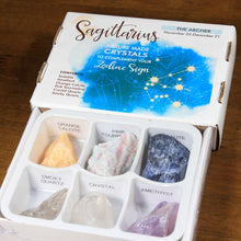 Load image into Gallery viewer, Sagittarius Horoscope Crystals from Rock Paradise. Photo shows a white box that has a blue ink blot with the Sagittarius constellation and illustrations of gemstones. The box reads &quot;Scorpio nature made crystals to complement your zodiac sign.&quot; Open box has 6 crystals in it.