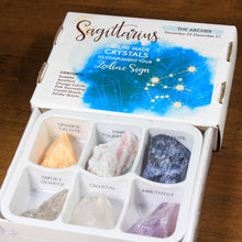 Load image into Gallery viewer, Sagittarius Horoscope Crystals from Rock Paradise. Photo shows a white box that has a blue ink blot with the Sagittarius constellation and illustrations of gemstones. The box reads "Scorpio nature made crystals to complement your zodiac sign." Open box has 6 crystals in it.