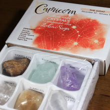 Load image into Gallery viewer, Capricorn Horoscope Crystals from Rock Paradise. Photo shows a white box that has a coral colored ink blot with the Capricorn constellation and illustrations of gemstones. The box reads "Capricorn nature made crystals to complement your zodiac sign. The Goat. December 22-January 19. Contents: Fluorite, Amethyst, Smoky Quartz, Citrine, Crystal Quartz, Tigers Eye."