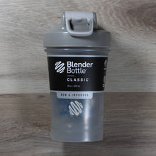 Load image into Gallery viewer, A photo of a clear bottle with a two tone grey lid, with a paper sleeve around it that says "Blender Bottle Classic"