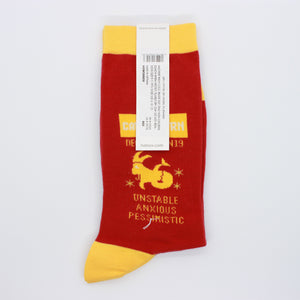 Capricorn socks by HOTSOX. The socks are red with yellow accents. This photo shows the right sock, which says "Capricorn December 22-January19. Unstable, anxious, pessimistic.."