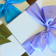 Load image into Gallery viewer, This photo shows an overhead view of three white gift boxes, each with different colored satin ribbon tied in a bow. The bows are purple, blue, and green.