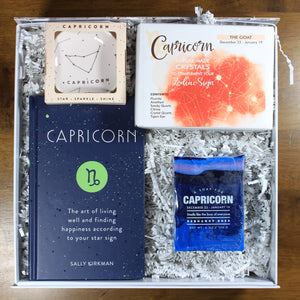 What's Your Sign Capricorn Gift Box: photo shows a white gift box with crinkle paper, filled with a Capricorn book, Capricorn ring dish, Capricorn crystals, and Capricorn soap.