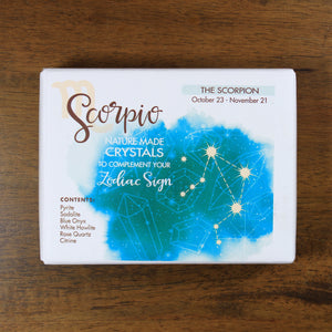 Scorpio Horoscope Crystals from Rock Paradise. Photo shows a white box that has a blue ink blot with the Scorpio constellation and illustrations of gemstones. The box reads "Scorpio nature made crystals to complement your zodiac sign."