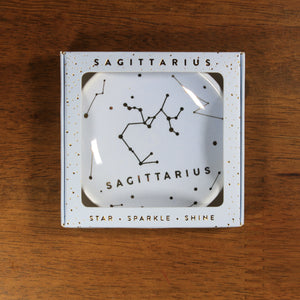 Sagittarius Zodiac Ring Dish from Lucky Feather. Light blue ring dish with gold print. Ring dish says Sagittarius and has an illustration of the Sagittarius constellation.