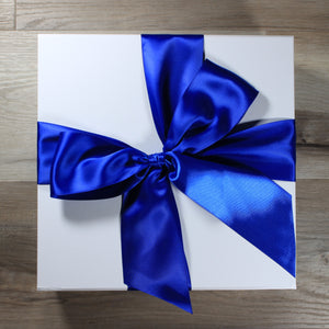A photo of a white box with a royal blue satin ribbon tied in a bow