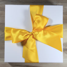Load image into Gallery viewer, An overhead view of a white magnetic square gift box with a yellow satin ribbon tied in a bow