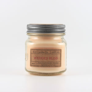 Mason Jar candle: an 8 oz mason jar with a metal cap, filled with off white wax, with a kraft paper label on the front that reads "Wedded Bliss"