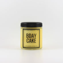 Load image into Gallery viewer, A yellow jar candle with a black lid from Posh Candle Co., that says &quot;Bday Cake&quot; on the front.