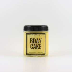 A yellow jar candle with a black lid from Posh Candle Co., that says "Bday Cake" on the front.