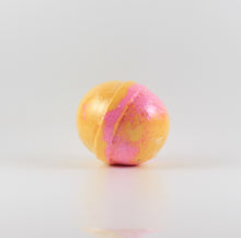Load image into Gallery viewer, A mostly yellow colored, oval shaped bath bomb with splashes of pink on a white background