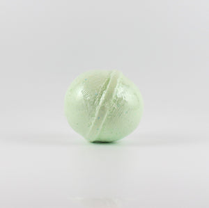 A light green colored, oval shaped bath bomb on a white background
