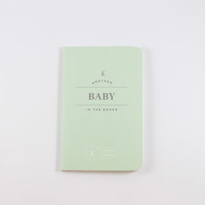 Small light mint green passport journal from Letterfolk with silver print that says "Another Baby in the books"