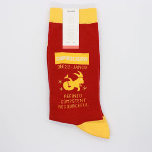 Capricorn socks by HOTSOX. The socks are red with yellow accents. This photo shows the left sock, which says "Capricorn December 22-January19. Refined, competent, resourceful."