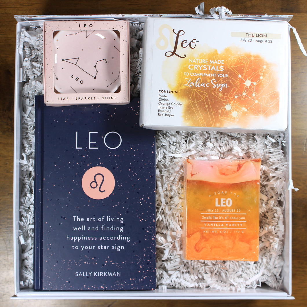 What's Your Sign Leo Gift Box: photo shows a white gift box with crinkle paper, filled with a Leo book, Leo ring dish, Leo crystals, and Leo soap.