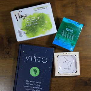 flat lay of what's your sign virgo zodiac gift box contents: zodiac crystals, soap, book and ring dish on wood table